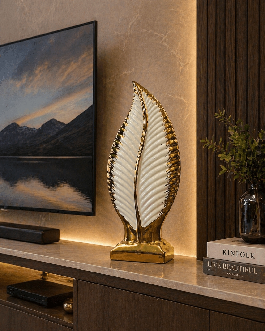 Modern white and gold leaf ceramic showpiece displayed on a living room TV console next to decorative books