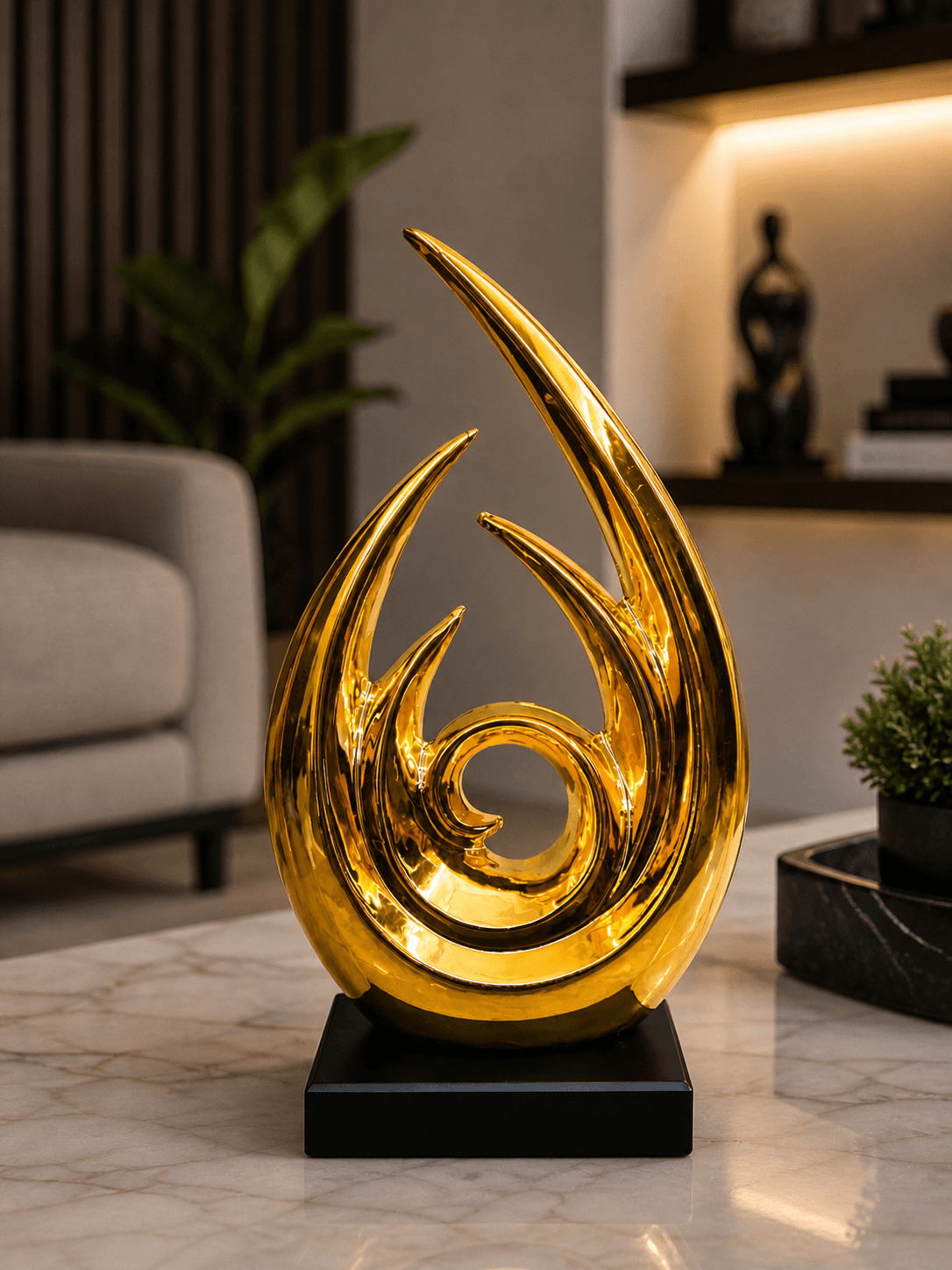 Glossy golden abstract flame sculpture on a black square base, styled on a marble center table in a modern luxury living room