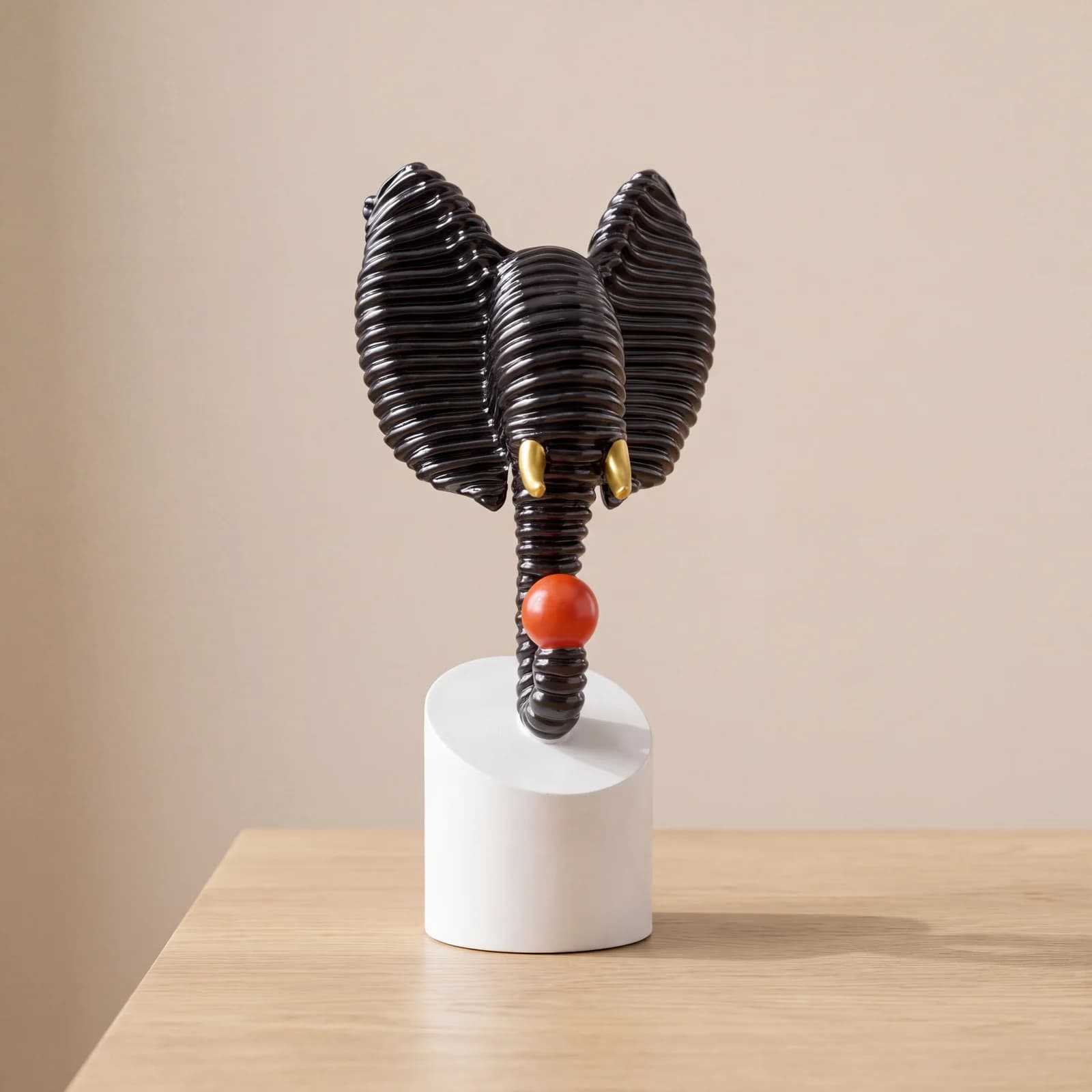 Abstract black textured elephant head sculpture holding a red ball, displayed on a modern living room side table over decorative books